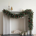 Frosted Christmas pine garland with pinecones and red berries draped on a white mantel