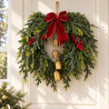 Christmas cedar wreath with red velvet bow and cascading gold bells on a white door